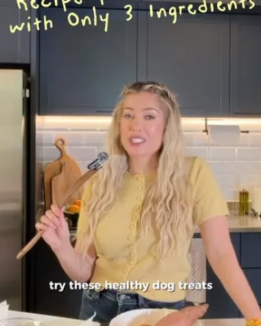 A woman in a yellow top holds a wooden spoon in her kitchen, with the caption “Try these healthy dog treats”